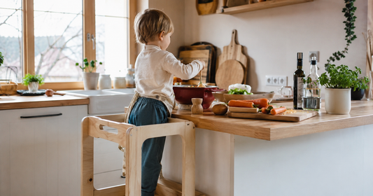 Enfant debout sur une tour d'observation en bois qui aide à préparer un repas en cuisine
